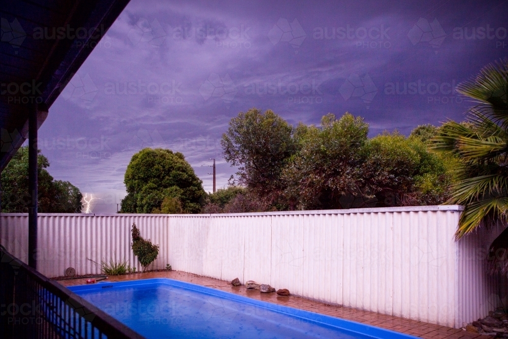 Lightning striking behind suburban pool and backyard - Australian Stock Image