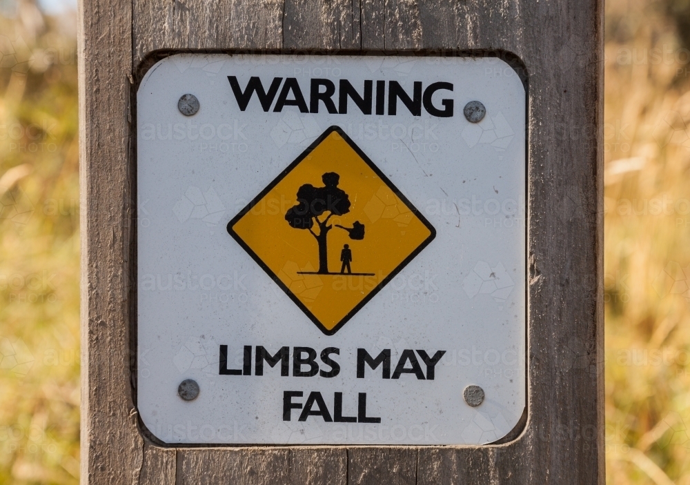 'Limbs may fall' warning sign on timber post - Australian Stock Image