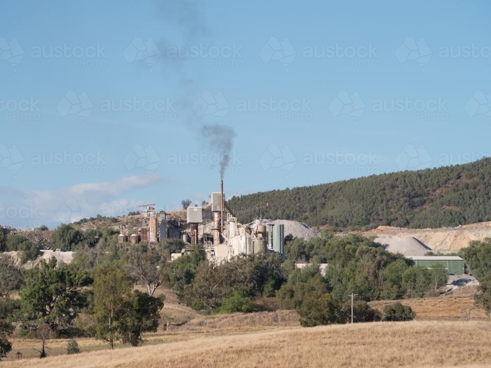 Limestone processing plant with chimney and smoke - Australian Stock Image
