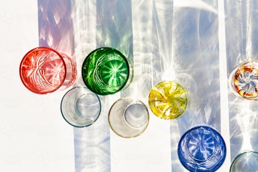 Line of brightly coloured glasses reflecting and bending light - Australian Stock Image