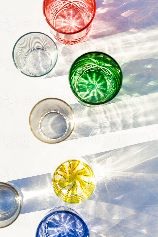Line of brightly coloured glasses reflecting and bending light - Australian Stock Image