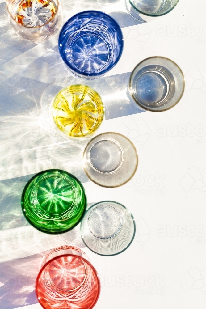 Line of brightly coloured glasses reflecting and bending light - Australian Stock Image