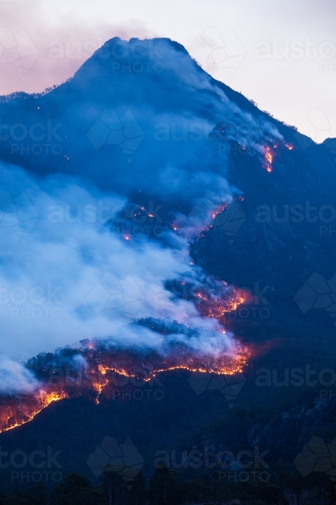 Line of fire crossing a mountain range at dusk - Australian Stock Image