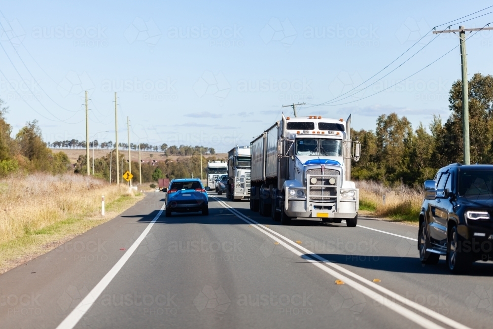 Line of trucks on highway hauling freight - Australian Stock Image