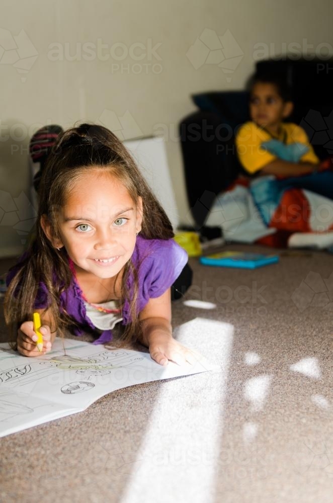 Little Aboriginal Australian Girl Drawing while on Floor - Australian Stock Image
