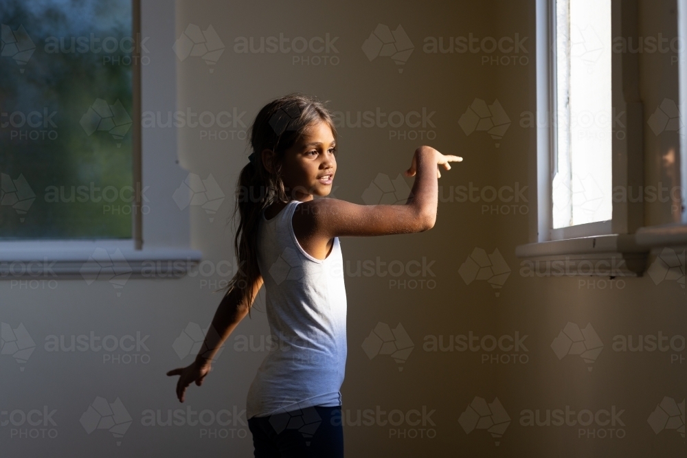 little aboriginal girl dancing by herself in bare room - Australian Stock Image