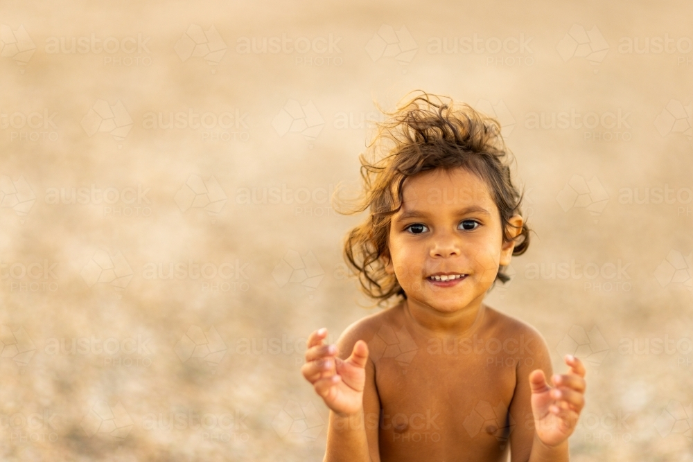 little aboriginal kid with hands in front in anticipation - Australian Stock Image