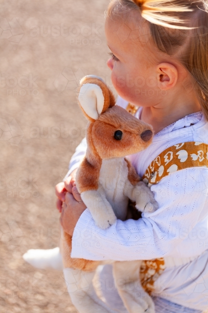 little Aussie girl with kangaroo plush toy outside - Australian Stock Image