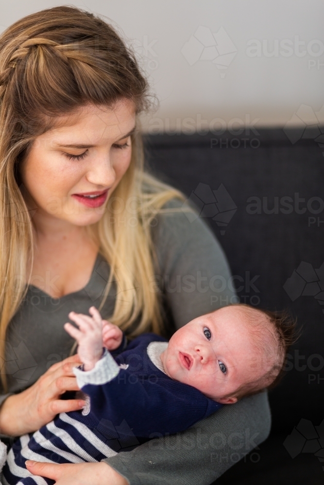 Little baby boy looking at camera from mothers arms - Australian Stock Image