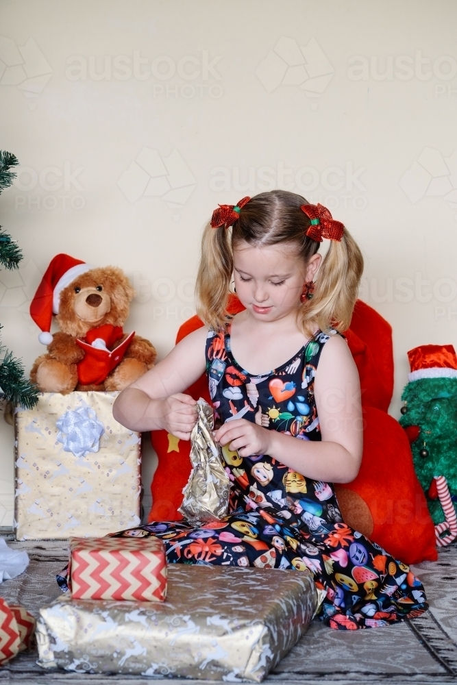 Little blonde girl unwrapping a Christmas present - Australian Stock Image