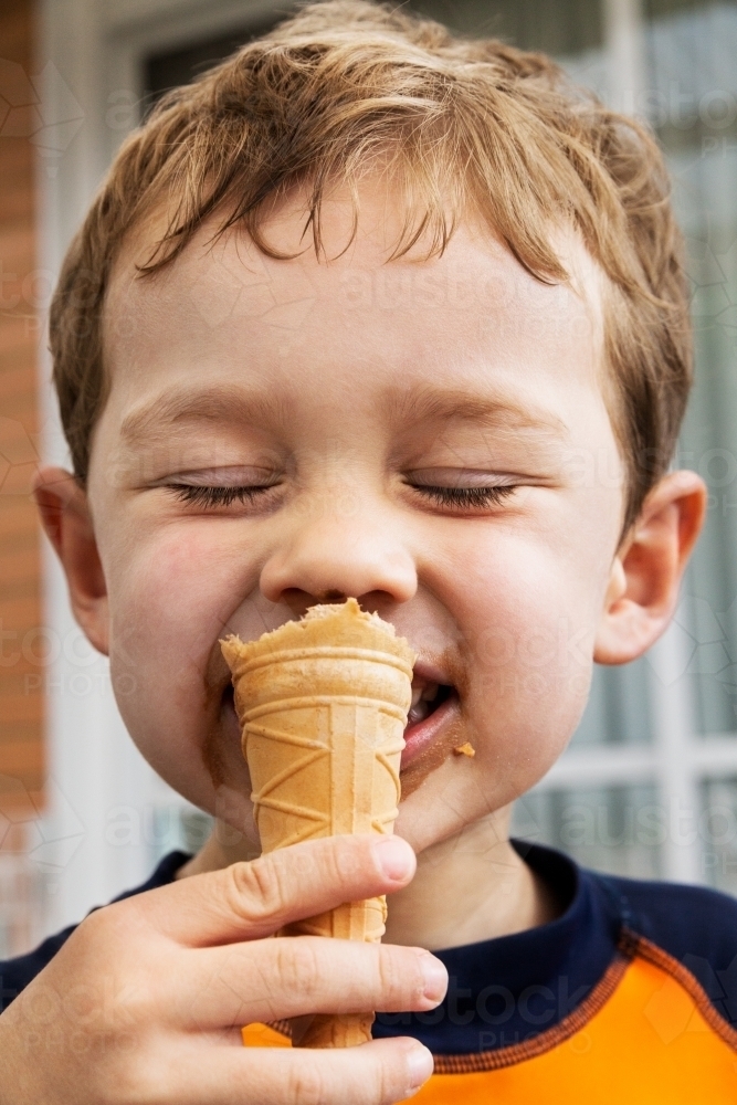 Little boy eating ice cream on a hot summer's day - Australian Stock Image