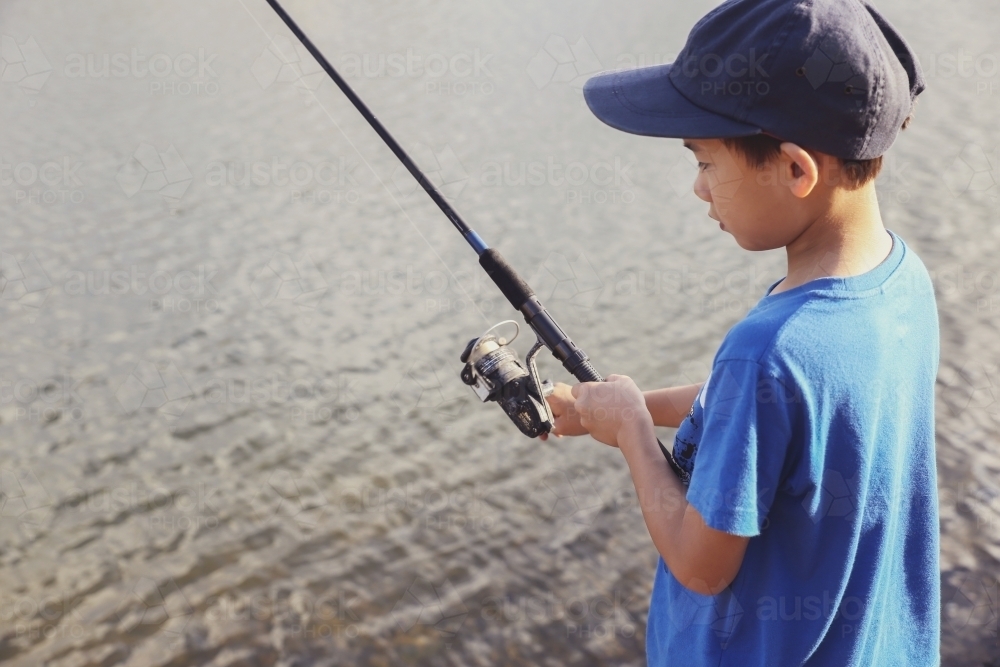 Little boy fishing  by the lake - Australian Stock Image