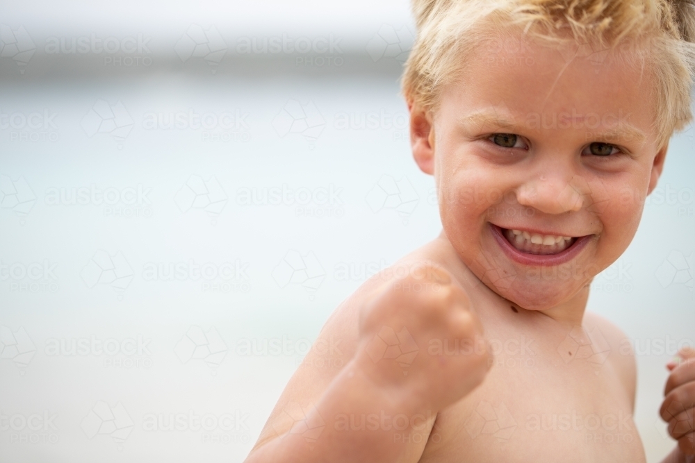 little boy flexing his muscles and clenching his fists - Australian Stock Image