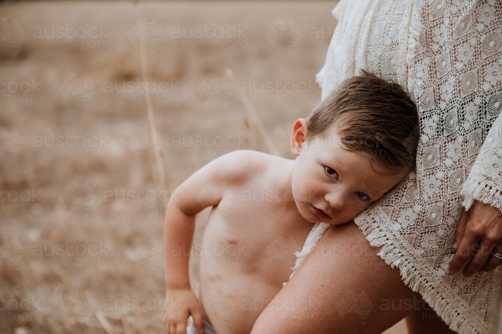 Little boy hugging mother's leg - Australian Stock Image