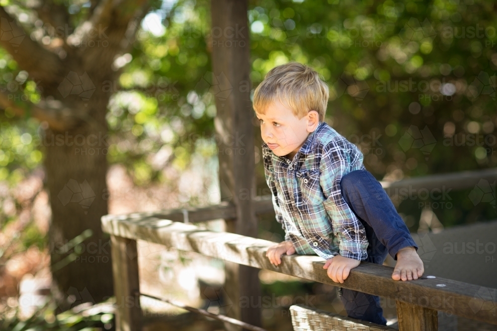 Little boy in checked shirt playing outdoors - Australian Stock Image