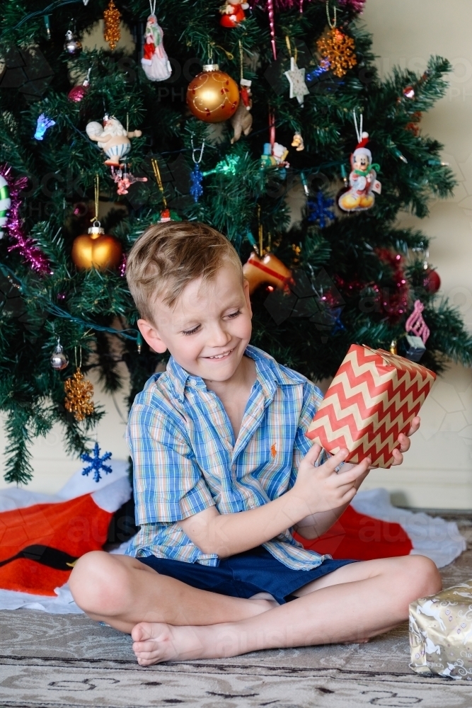 Little boy looking at a Christmas gift excitedly - Australian Stock Image