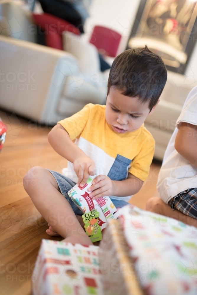 Little boy opening Christmas presents at home - Australian Stock Image