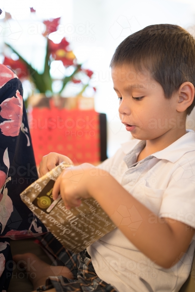 Little boy opening Christmas presents at home - Australian Stock Image