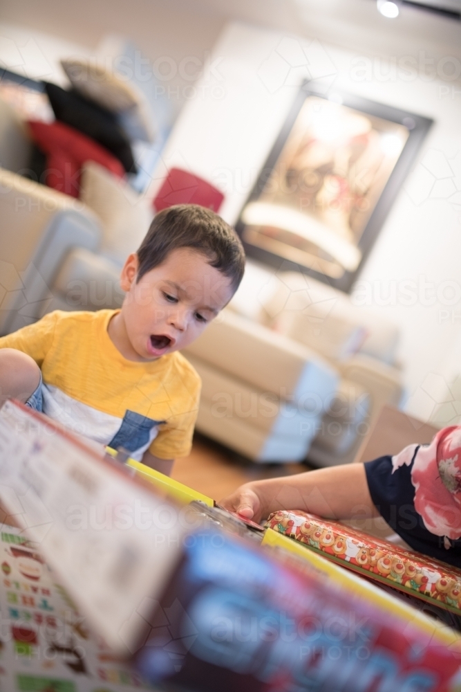 Little boy opening Christmas presents at home - Australian Stock Image