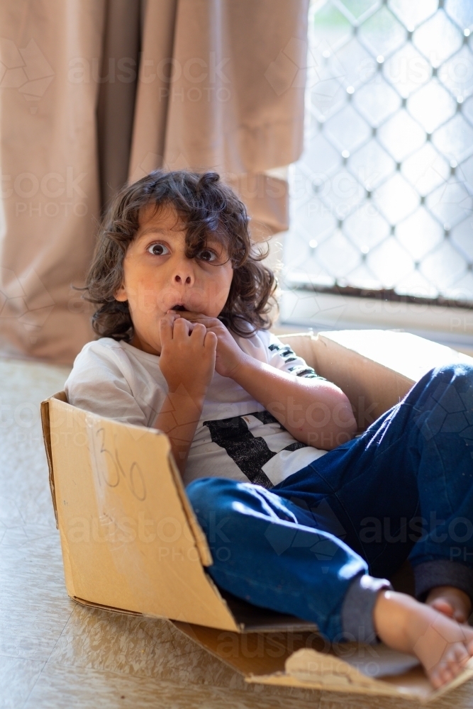 Little boy playing in a cardboard box - Australian Stock Image