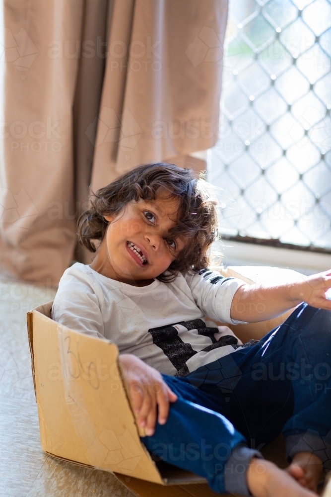Little boy playing in a cardboard box - Australian Stock Image