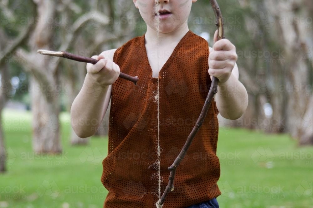 Little boy playing with homemade bow and arrow - Australian Stock Image