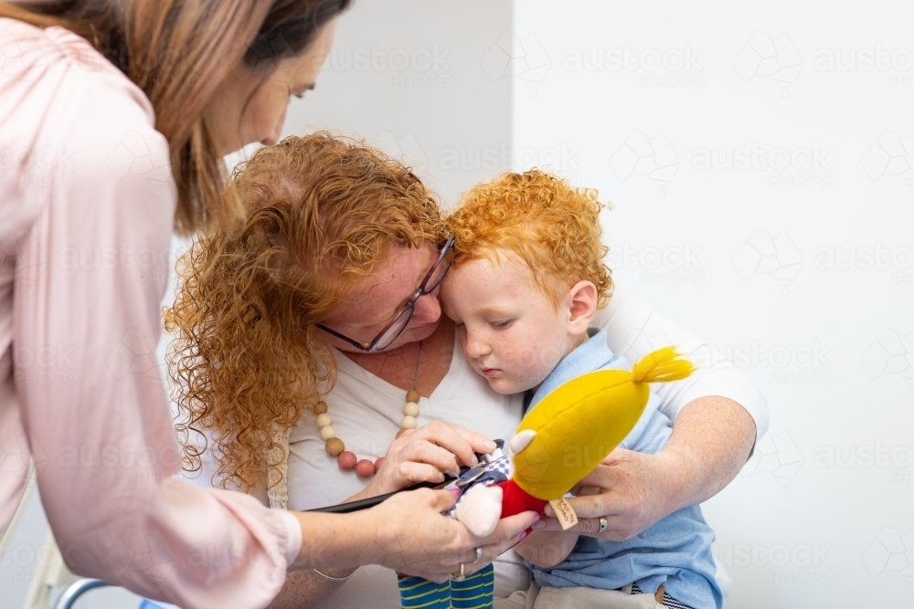 little boy sitting on mum's lap with health professional - Australian Stock Image
