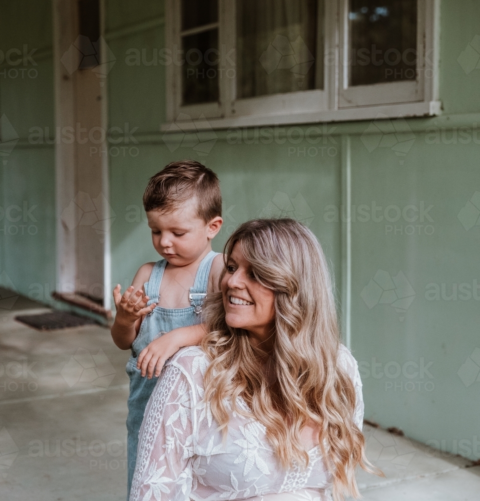 Little boy talking with his mother on the steps of front verandah - Australian Stock Image