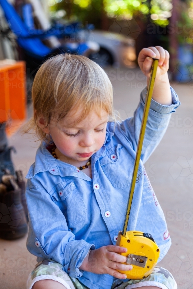 Image of Little boy with yellow tape measure measuring how high he is ...