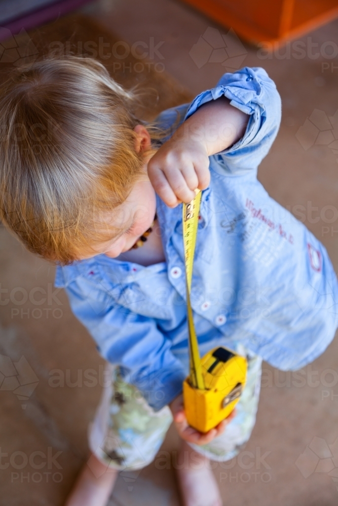 Image of Little boy with yellow tape measure measuring how high he is ...