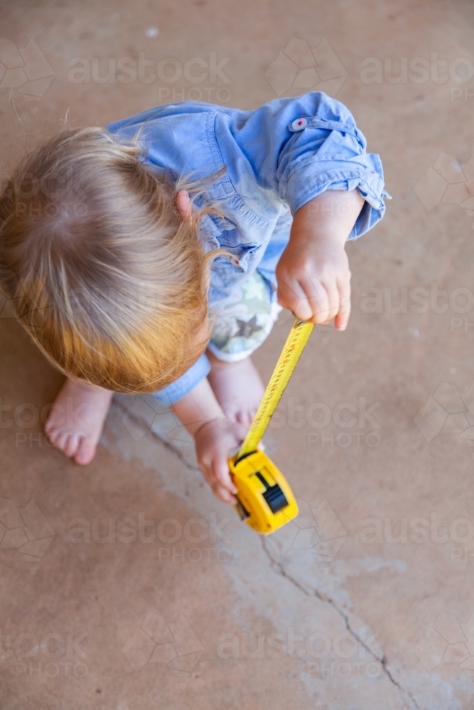 Image of Little boy with yellow tape measure measuring how high he is ...