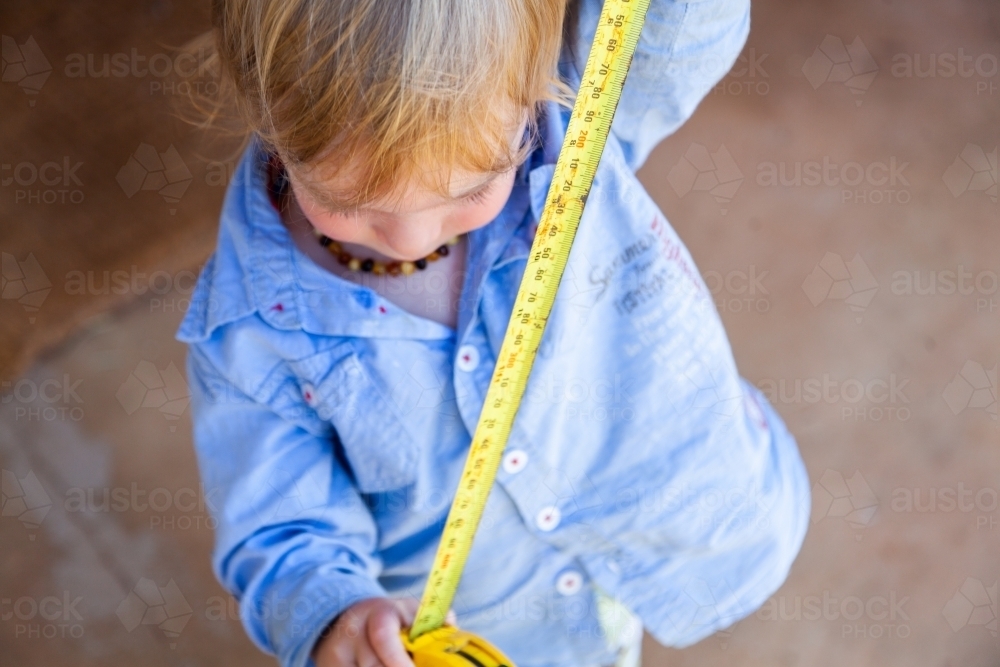 Image of Little boy with yellow tape measure measuring how high he is ...