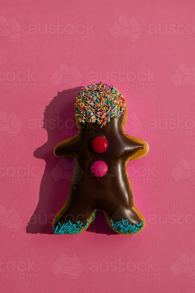 little donut man on red background, with hard shadow - Australian Stock Image