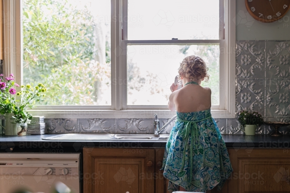 Little girl at kitchen sink - Australian Stock Image