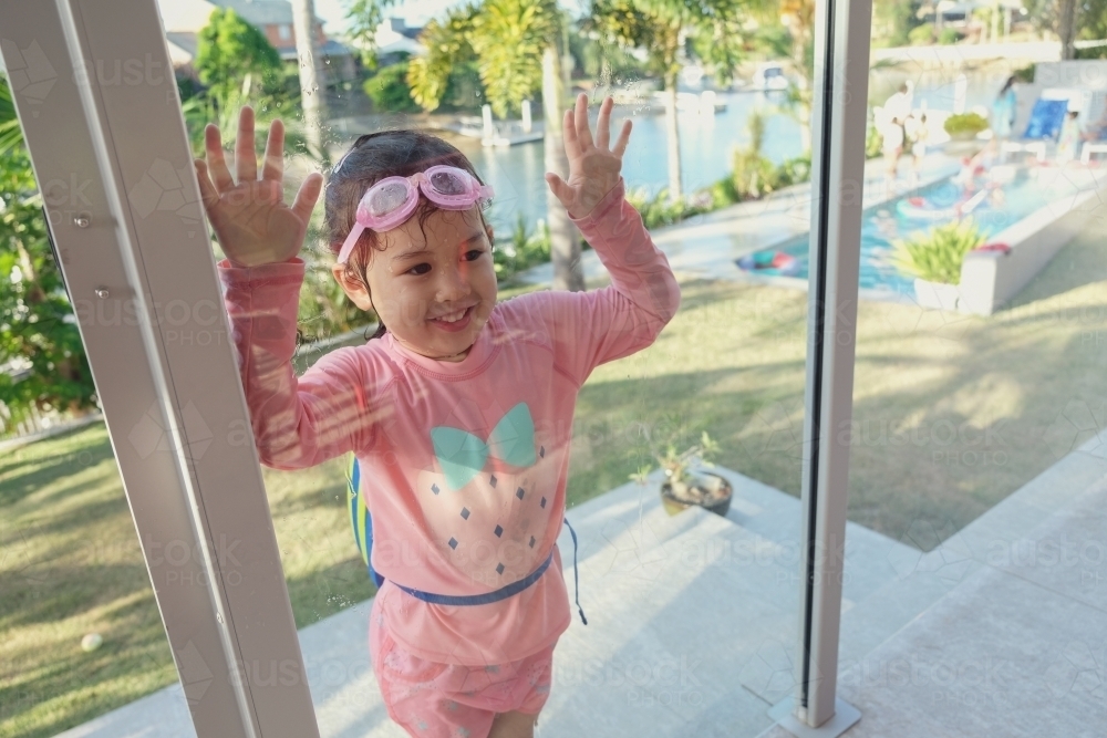 Little girl by pool glass fencing - Australian Stock Image