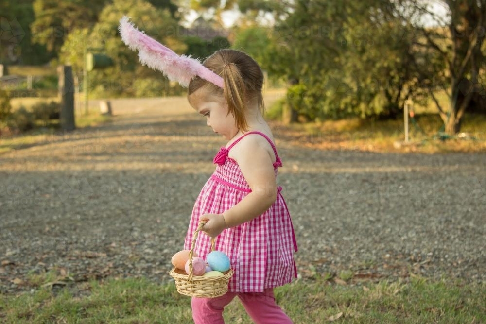 Little girl carrying a basket of Easter eggs - Australian Stock Image