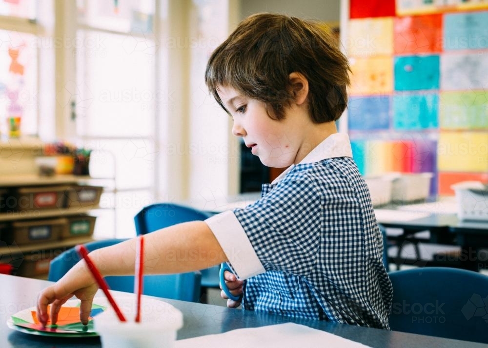 Little girl cutting & pasting in the classroom - Australian Stock Image
