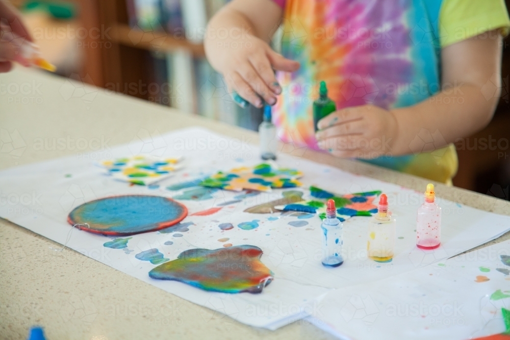Little girl doing colourful Christmas craft with food colouring paint - Australian Stock Image