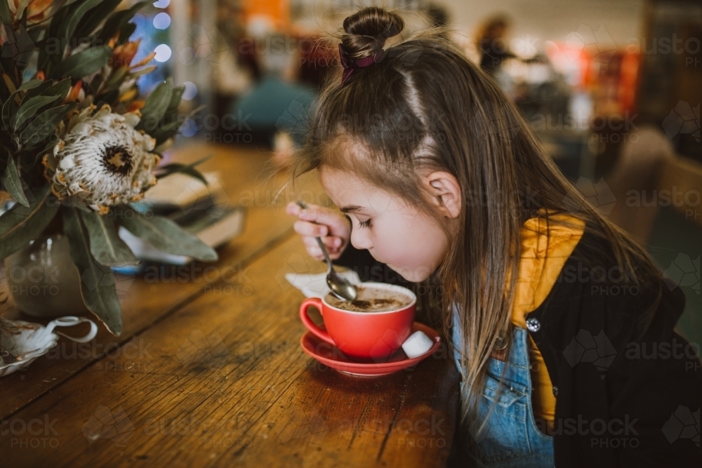 Little girl drinking a hot chocolate - Australian Stock Image