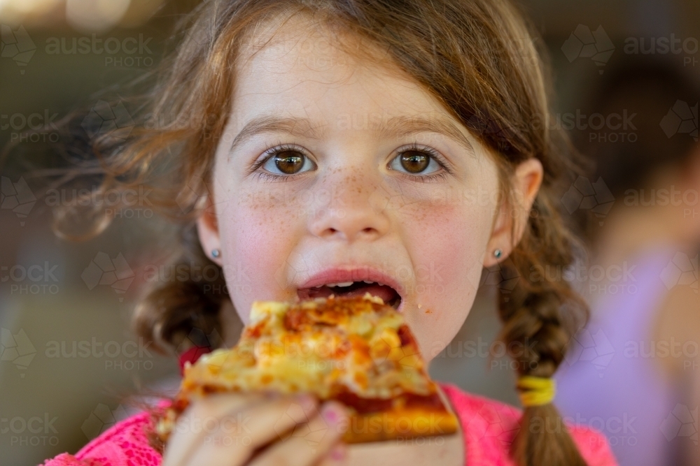 Little girl eating a huge slice of pizza - Australian Stock Image