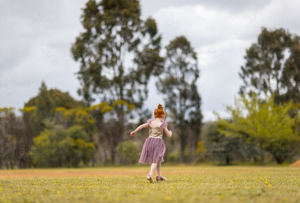 little girl from behind running away in parkland setting - Australian Stock Image