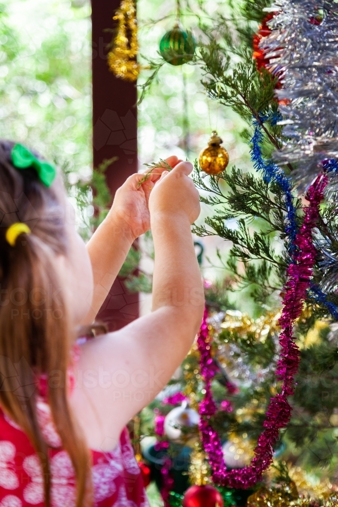 Little girl hanging baubles on Christmas tree - Australian Stock Image