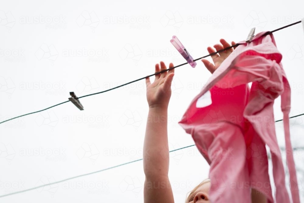 Little girl hanging clothes on the line - Australian Stock Image