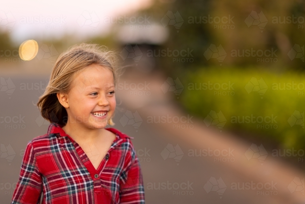 little girl happily smiling in evening light - Australian Stock Image