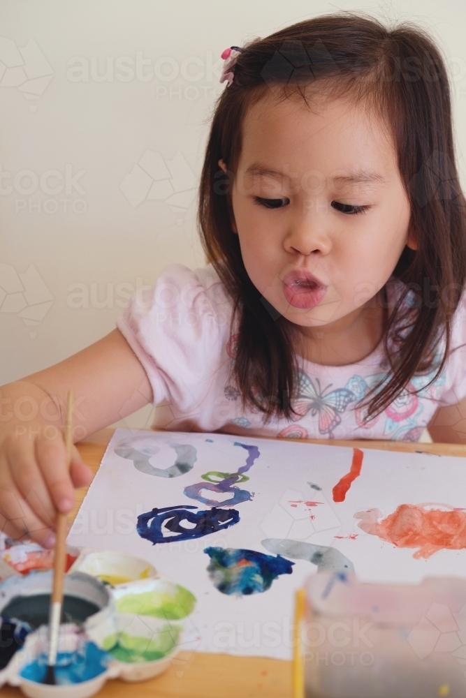 Little girl having fun painting at home - Australian Stock Image