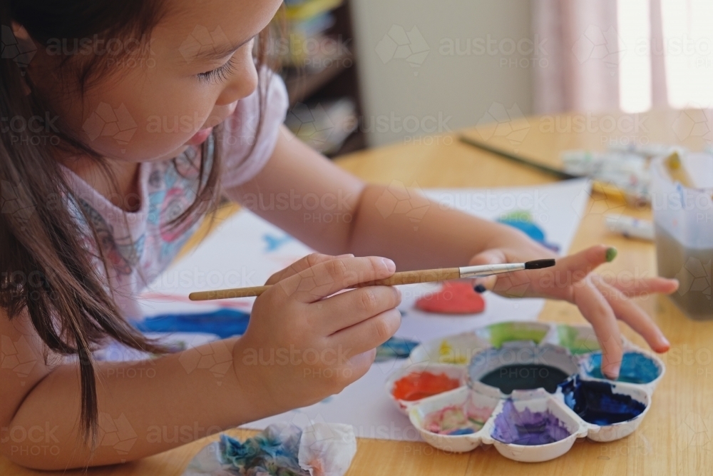 Little girl having fun painting at home - Australian Stock Image