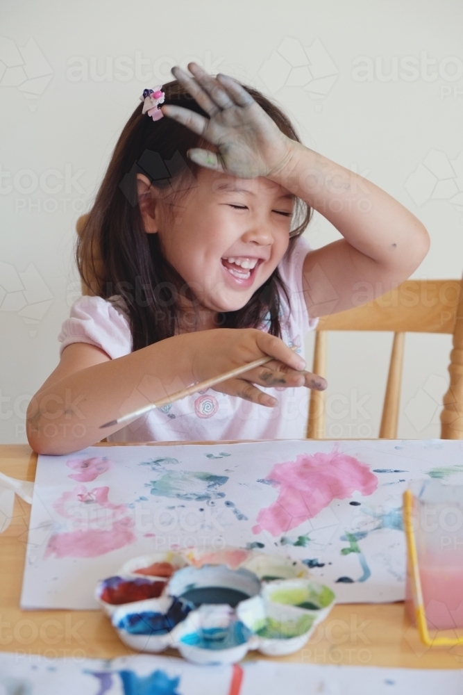 Little girl having fun painting at home - Australian Stock Image