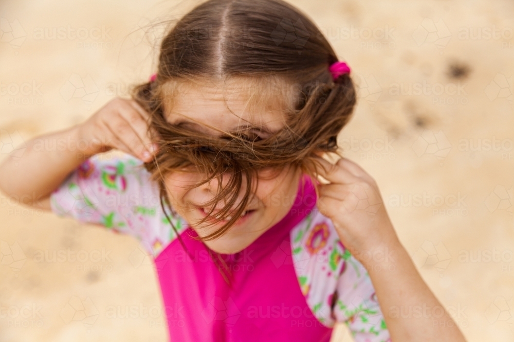 Little girl hiding in hair at beach - Australian Stock Image