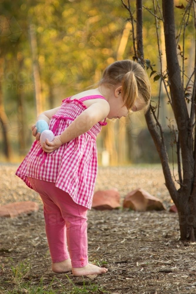 Little girl holding Easter eggs behind her back - Australian Stock Image