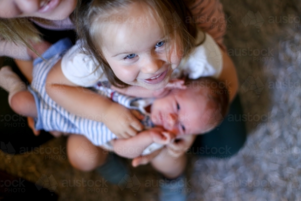 Little girl holding her newborn sibling - Australian Stock Image